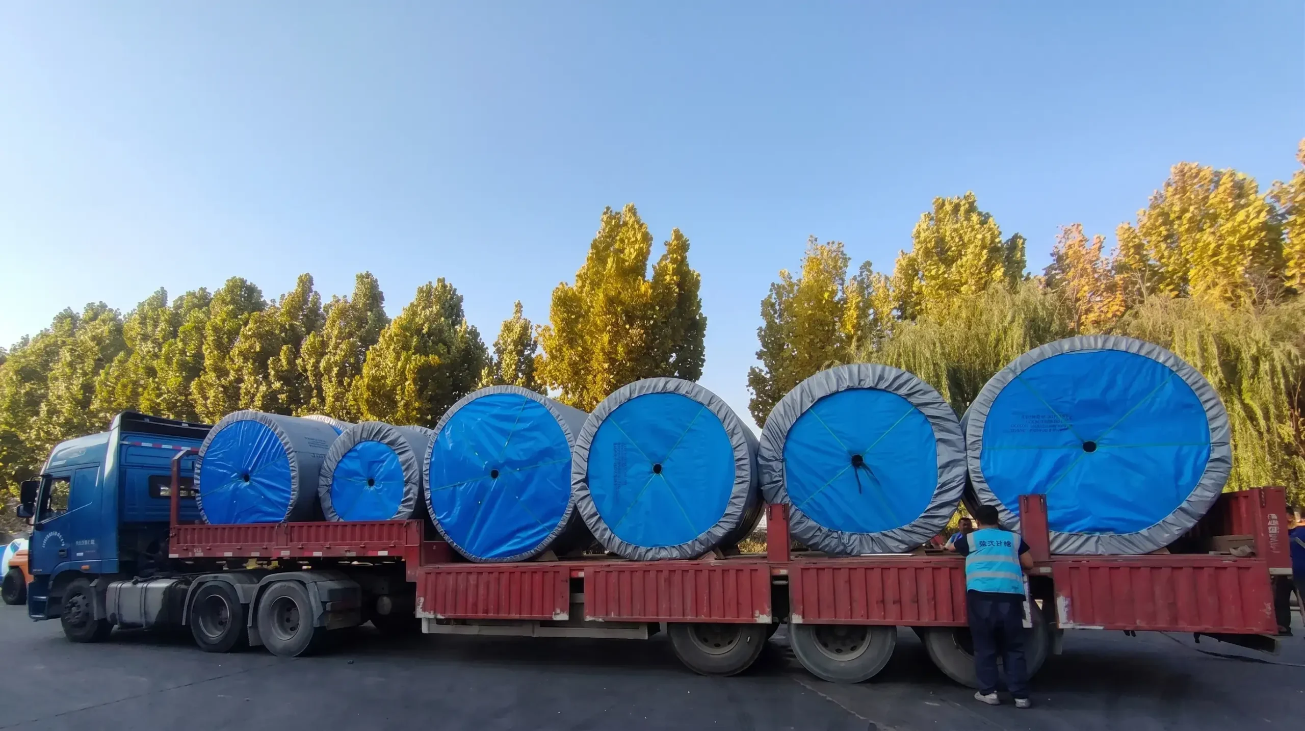 Heavy duty rubber conveyor belt rolls loaded on flatbed truck for export delivery to mining and industrial projects